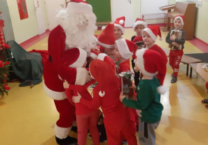 Dzieci żegnają się z Mikołajem grupowym uściskiem.